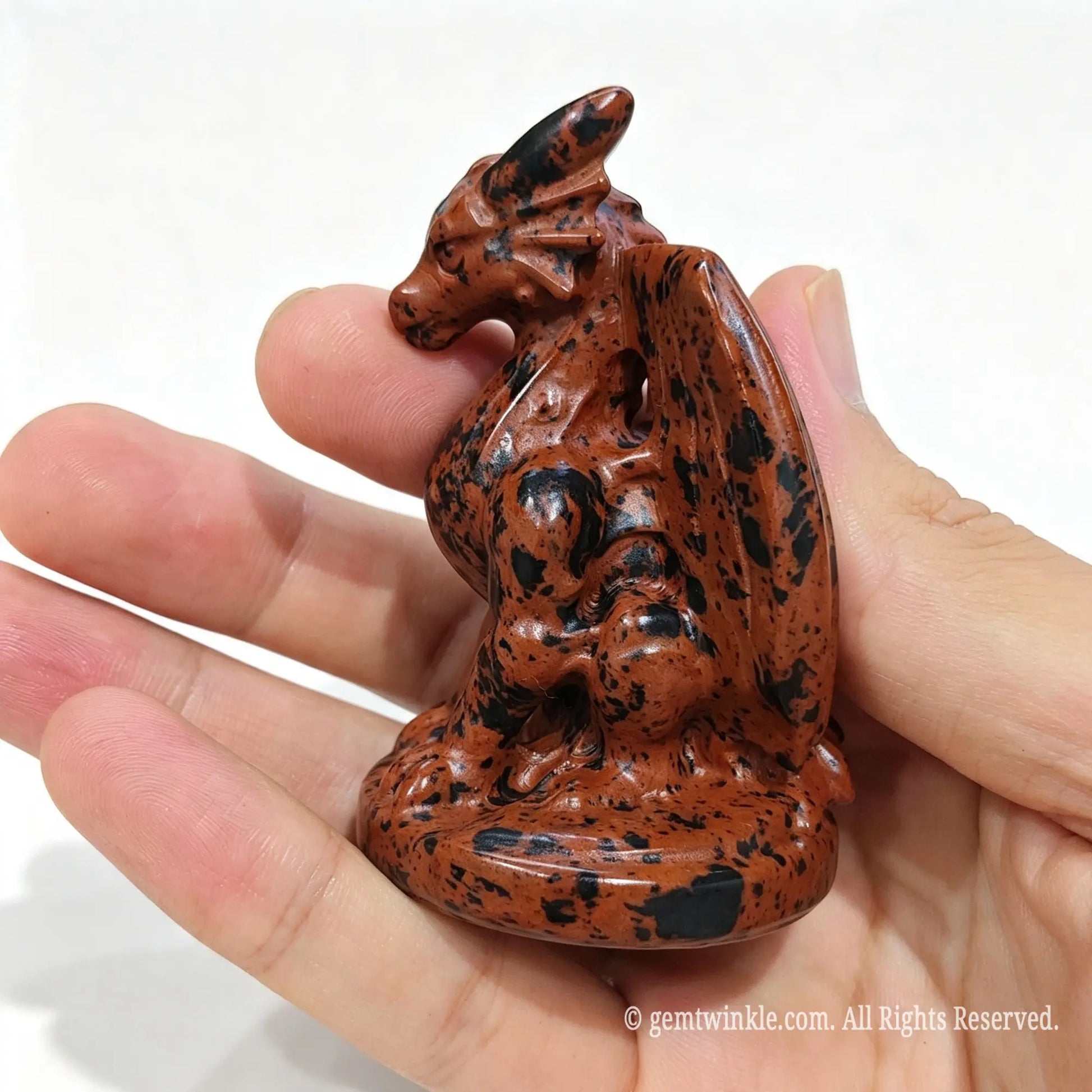 Single mahogany obsidian dragon figurine 7cm held in hand showing folded wings and detailed head structure
