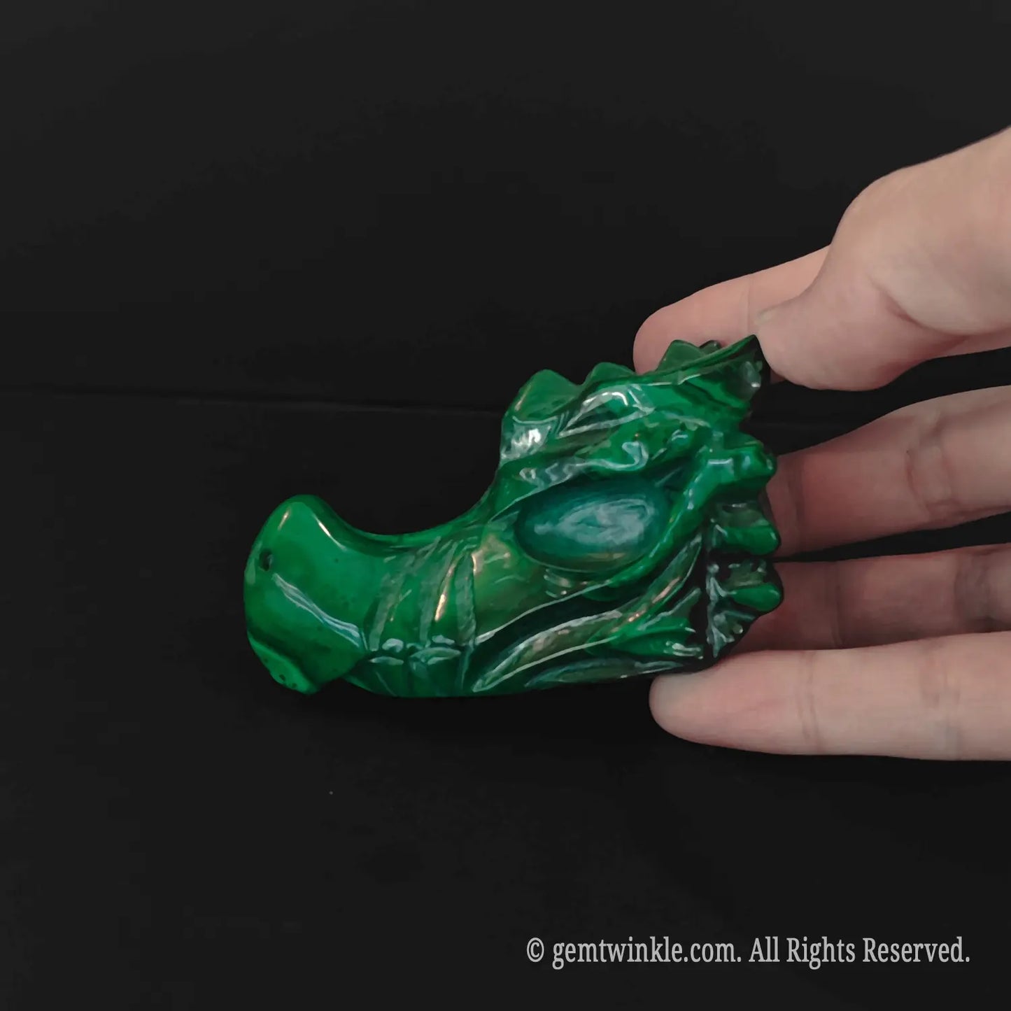 Side profile view of natural malachite dragon carving showing organic mineral textures