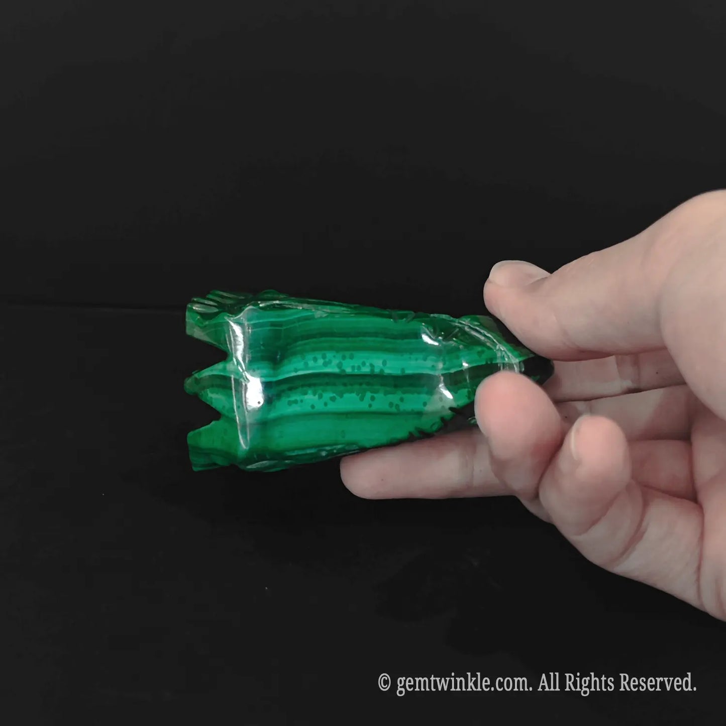 Top view of malachite dragon carving displaying concentric green mineral bands