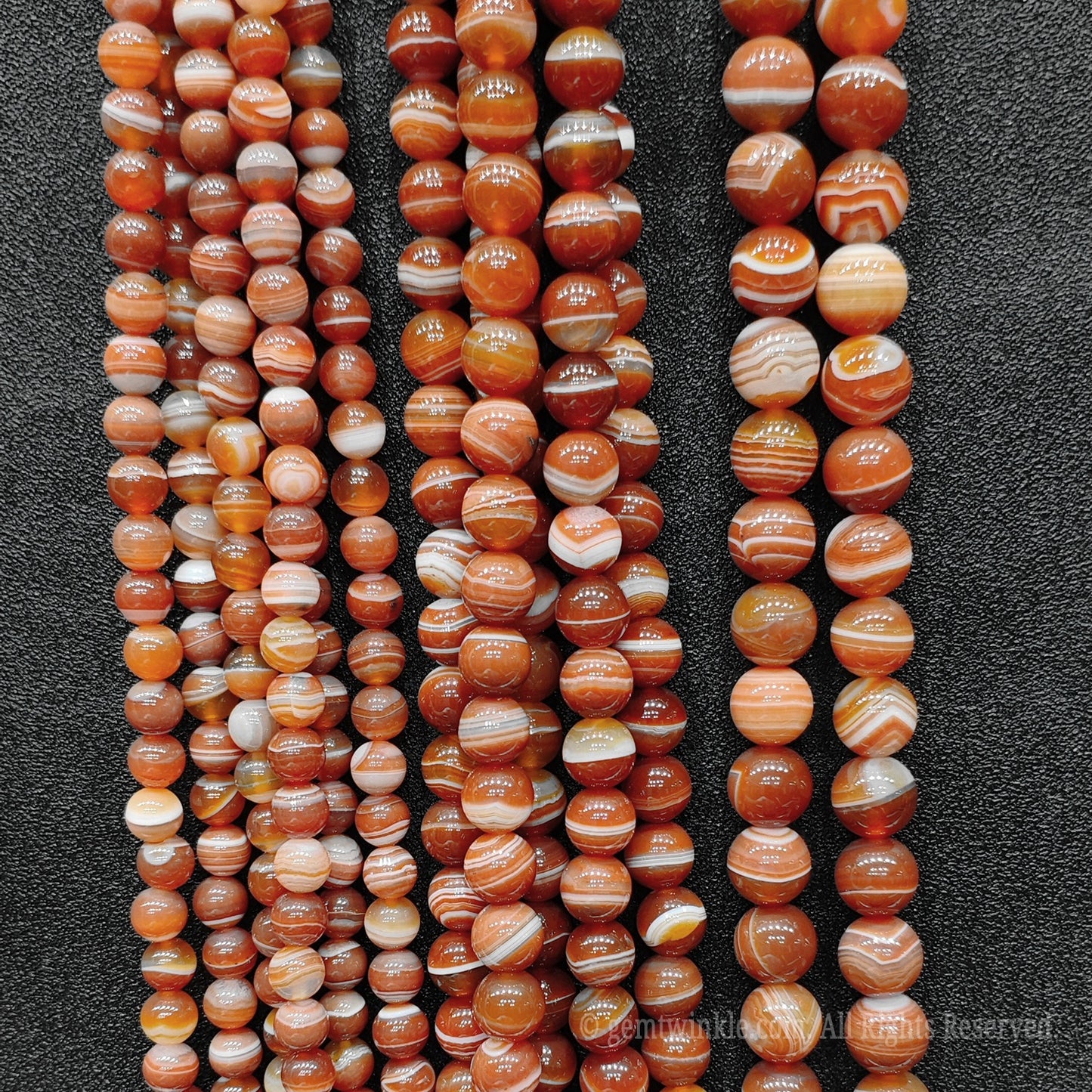 Large vertical collection of handpicked red striped agate round loose beads for commercial jewelry factories and high volume boutique sourcing