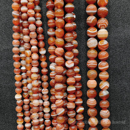 Large vertical collection of handpicked red striped agate round loose beads for commercial jewelry factories and high volume boutique sourcing