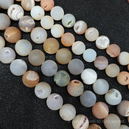 Detailed view of multiple matte agate stone beads with clear mineral banding and tiny sparkling druzy crystal pockets for jewelry making