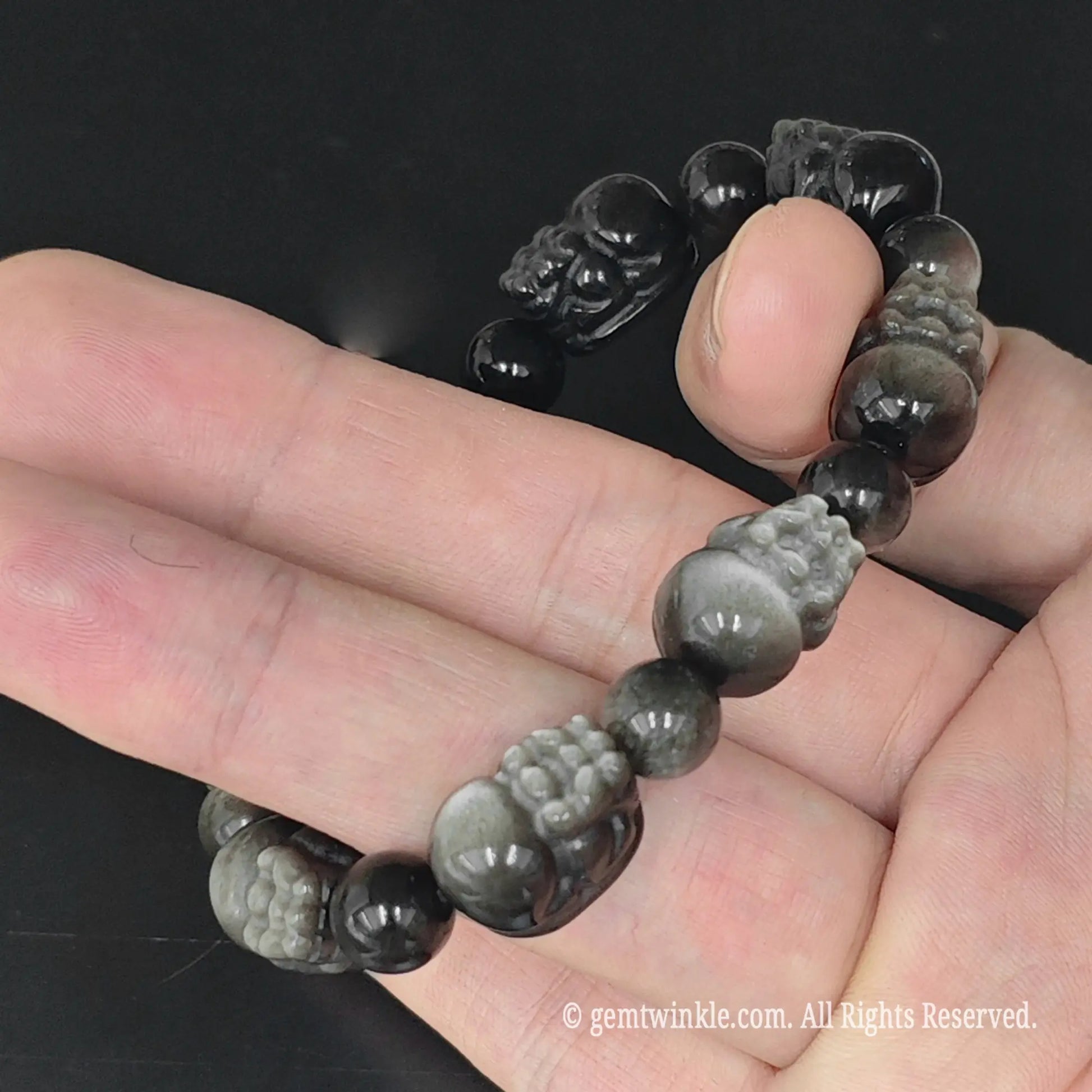 top view of metallic silver flash obsidian pixiu stretch bangle held in palm