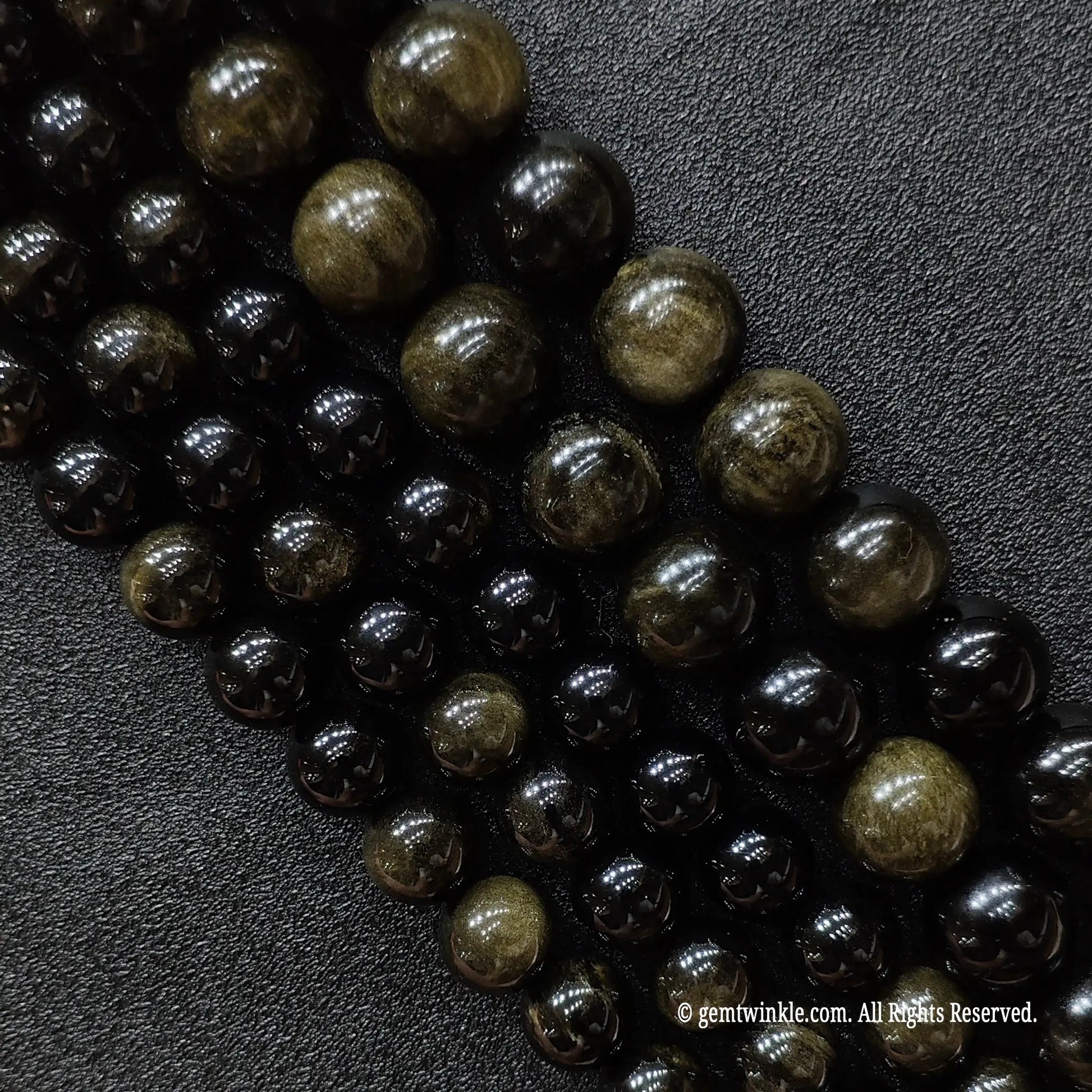 Close up of natural black gold sheen obsidian crystal beads strands showing subtle gold flash reflections