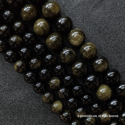 Close up of natural black gold sheen obsidian crystal beads strands showing subtle gold flash reflections