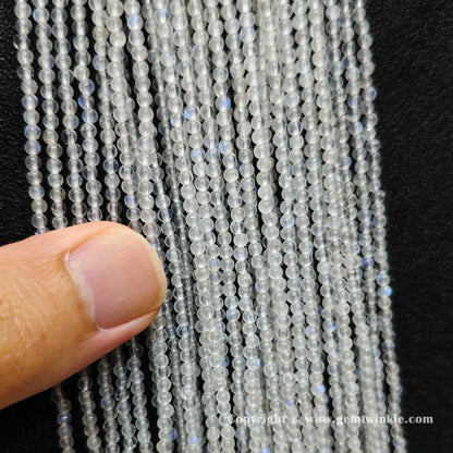Close up view of 2mm micro blue flash moonstone seed beads inspected on hand for optical sheen preview