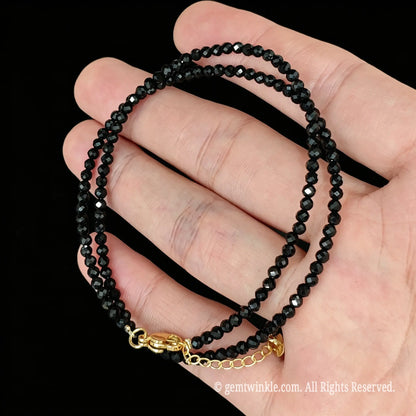 close up view of gold tone lobster clasp, extender chain and metal tag on black tourmaline necklace