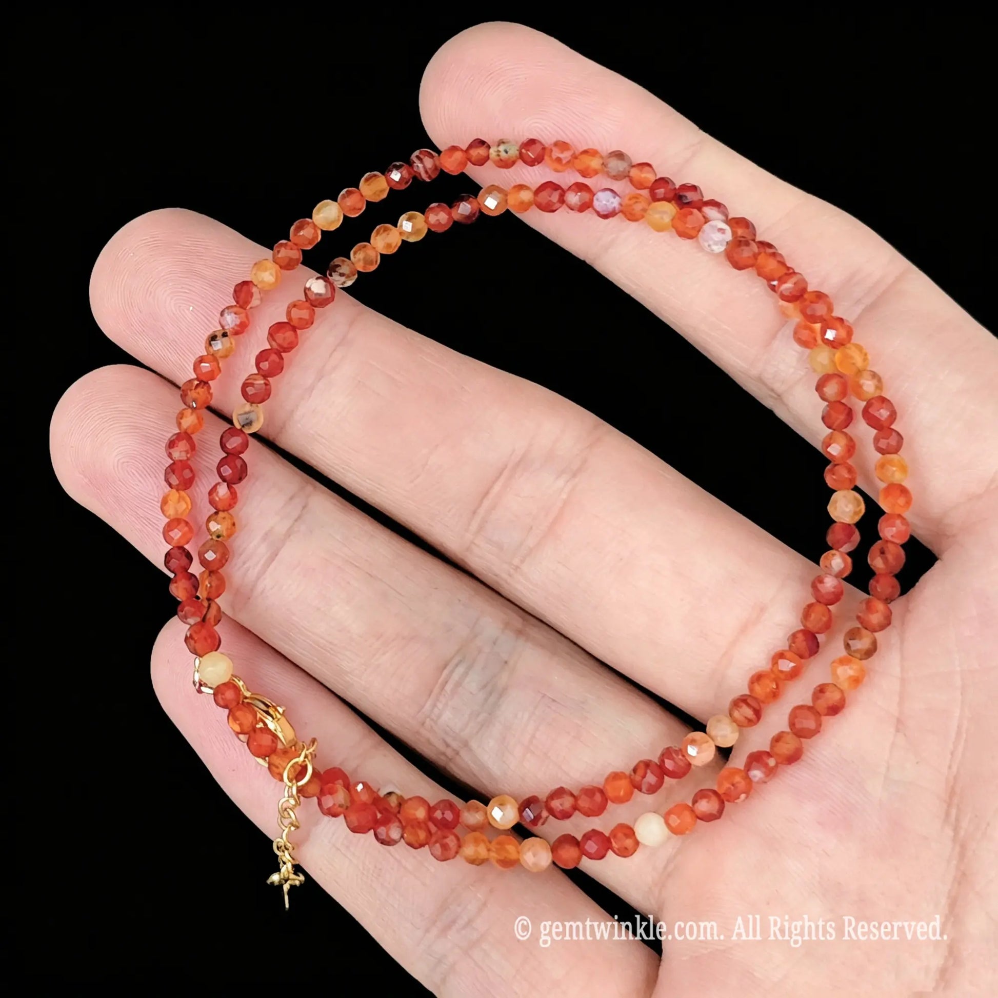 close up of gold tone lobster clasp and 5cm extension chain on red banded agate necklace