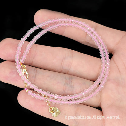 close up view of gold tone lobster clasp, extender chain and butterfly charm tag on rose quartz necklace