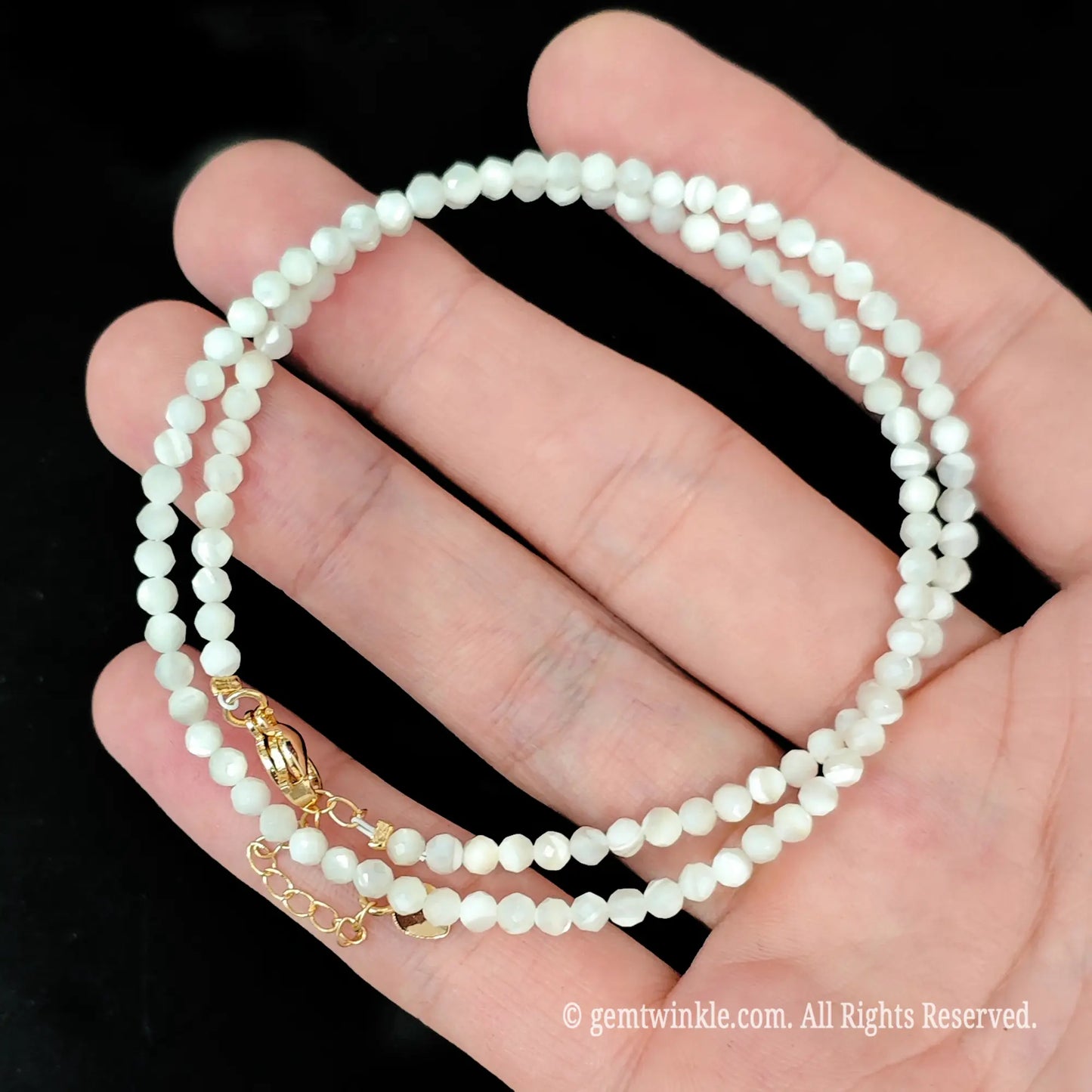 detailed view of gold tone extender chain on white mother of pearl bead necklace