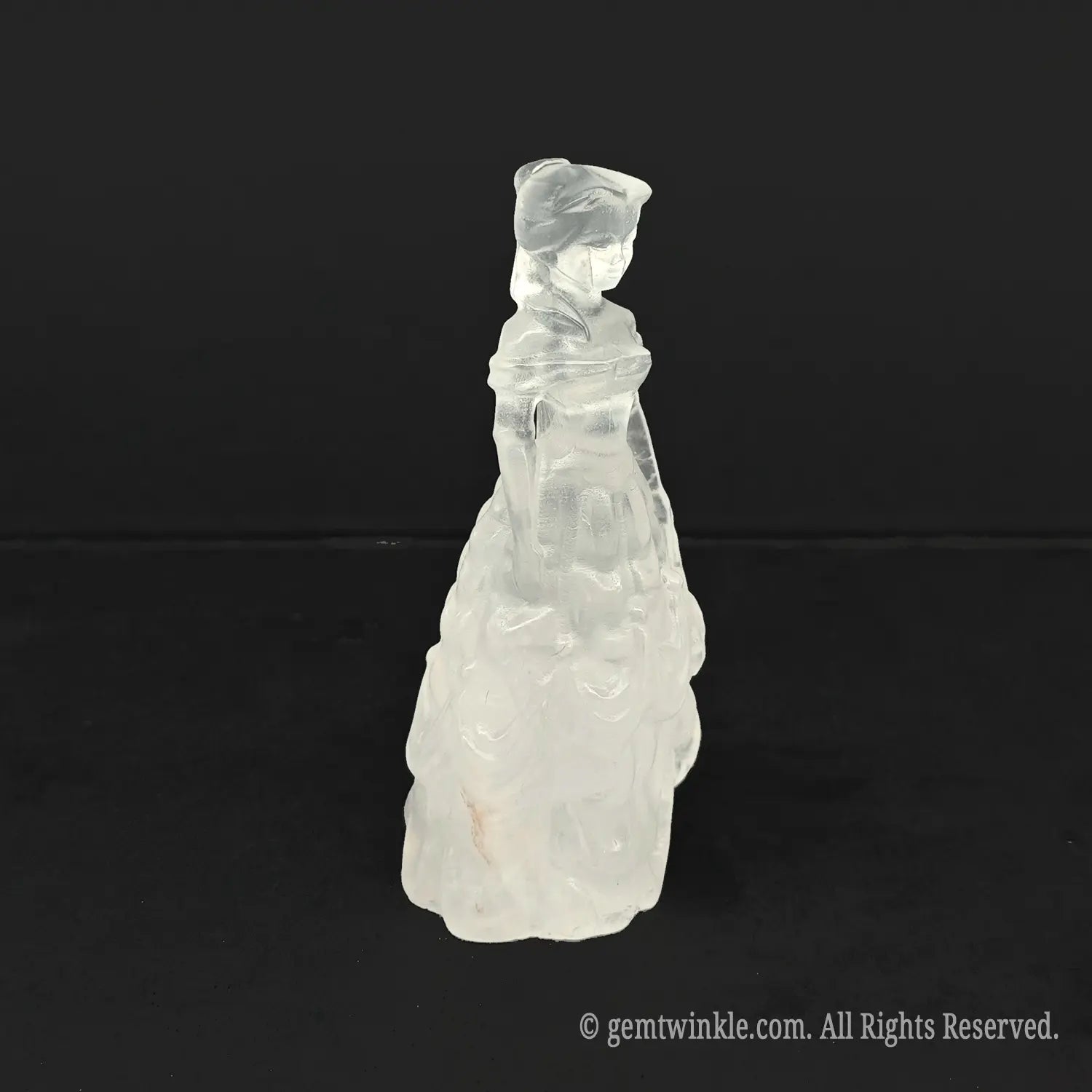 Side view of an opaque milky quartz queen figurine, showcasing detailed dress ruffle layers and smooth polished stone finish