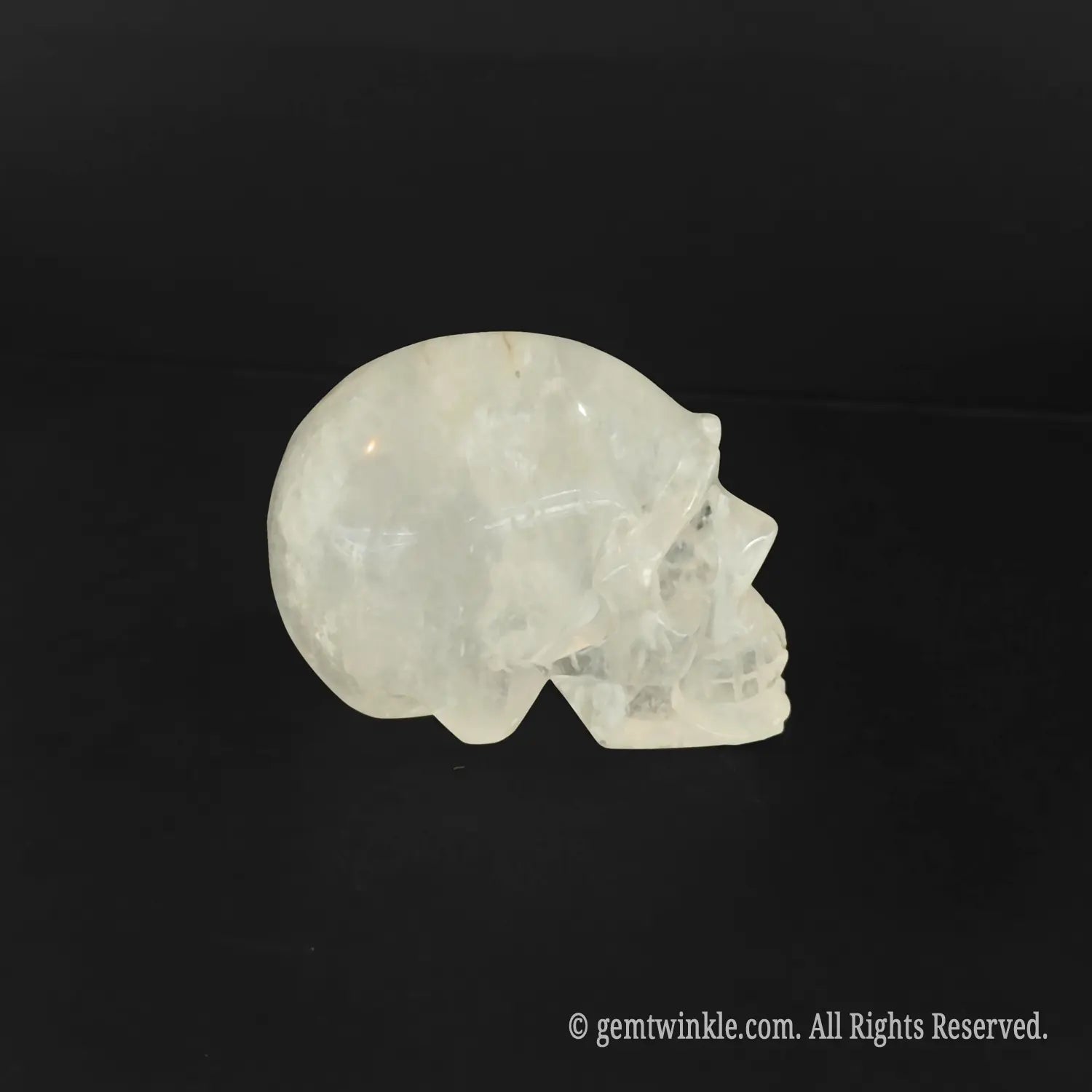 Side profile of milky white quartz skull carving highlighting natural mineral veils and non-transparent structure