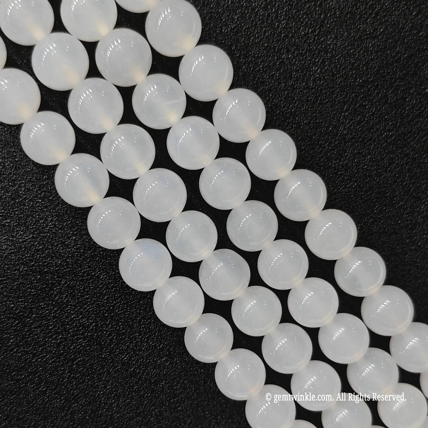 Close up view of milky white agate round beads highlighting consistent smooth cut and porcelain sheen