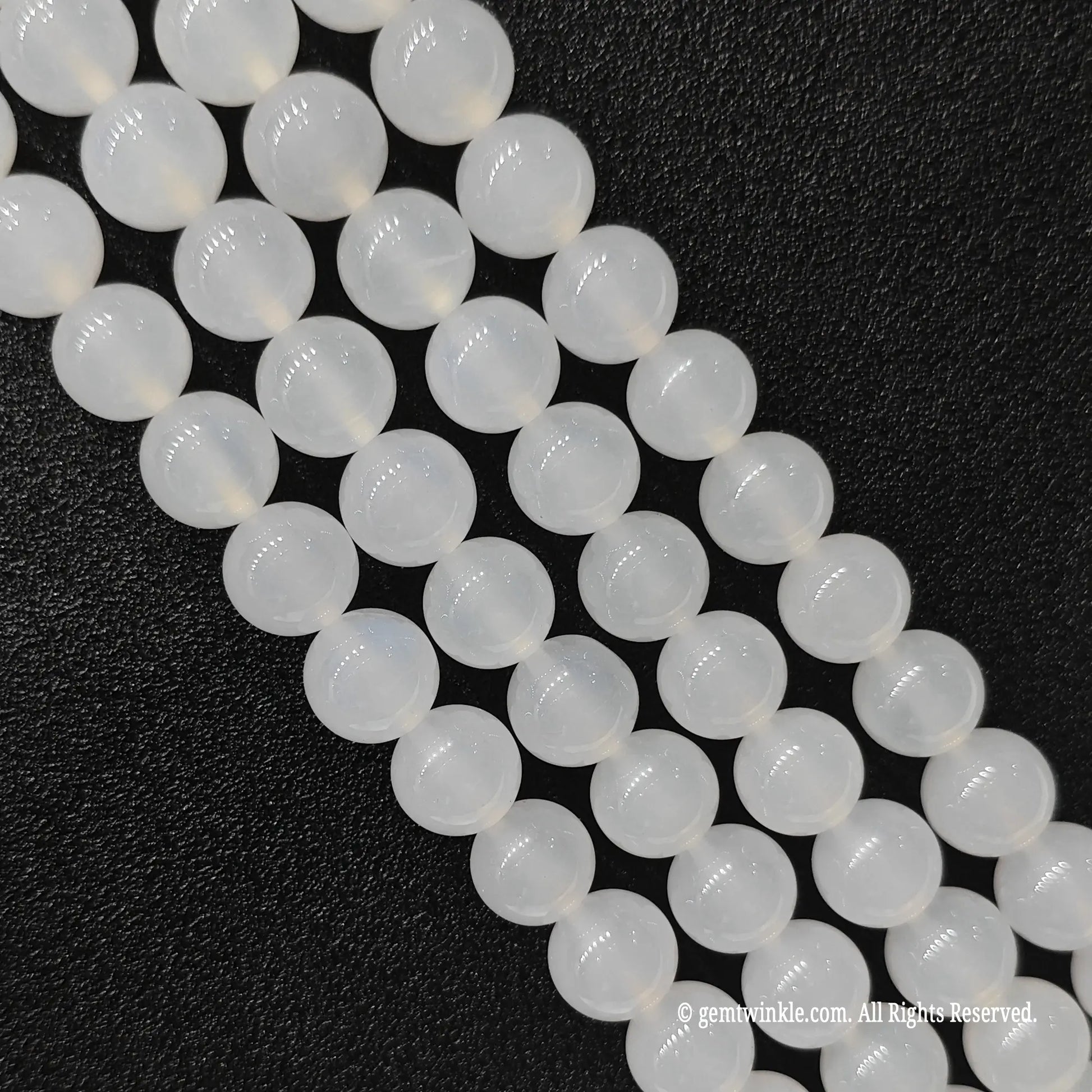 Close up view of milky white agate round beads highlighting consistent smooth cut and porcelain sheen