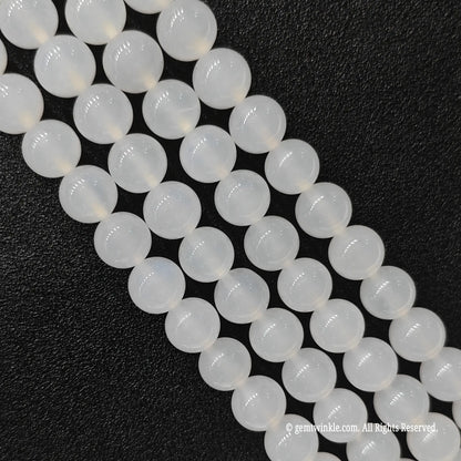 Close up view of milky white agate round beads highlighting consistent smooth cut and porcelain sheen