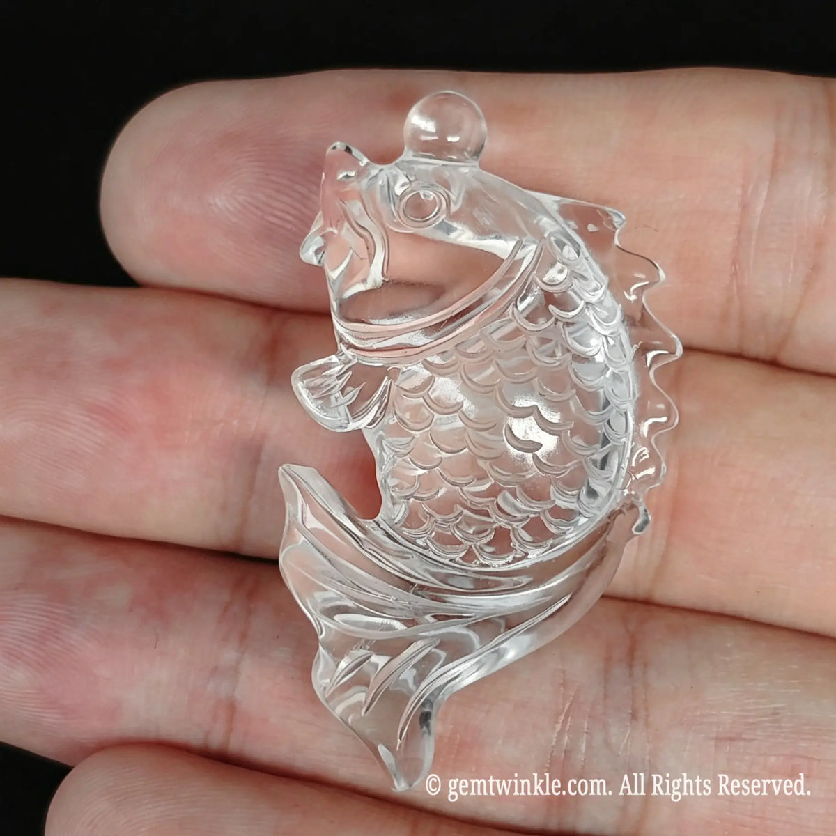 Hand preview of a 30mm clear quartz koi fish carving showing high transparency and gloss finish