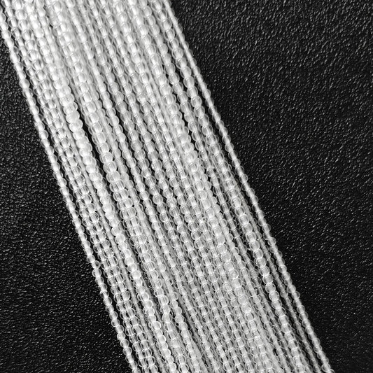 Macro closeup of mini clear quartz smooth round seed beads showing translucent body