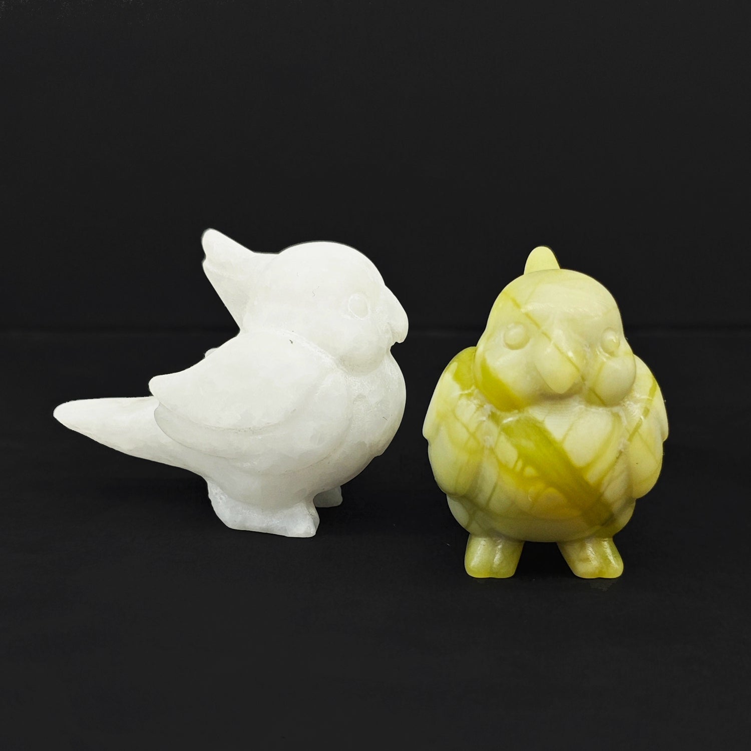 Front and side profile views of two miniature gemstone parrot carvings showcasing detailed head crests and hand polished wings