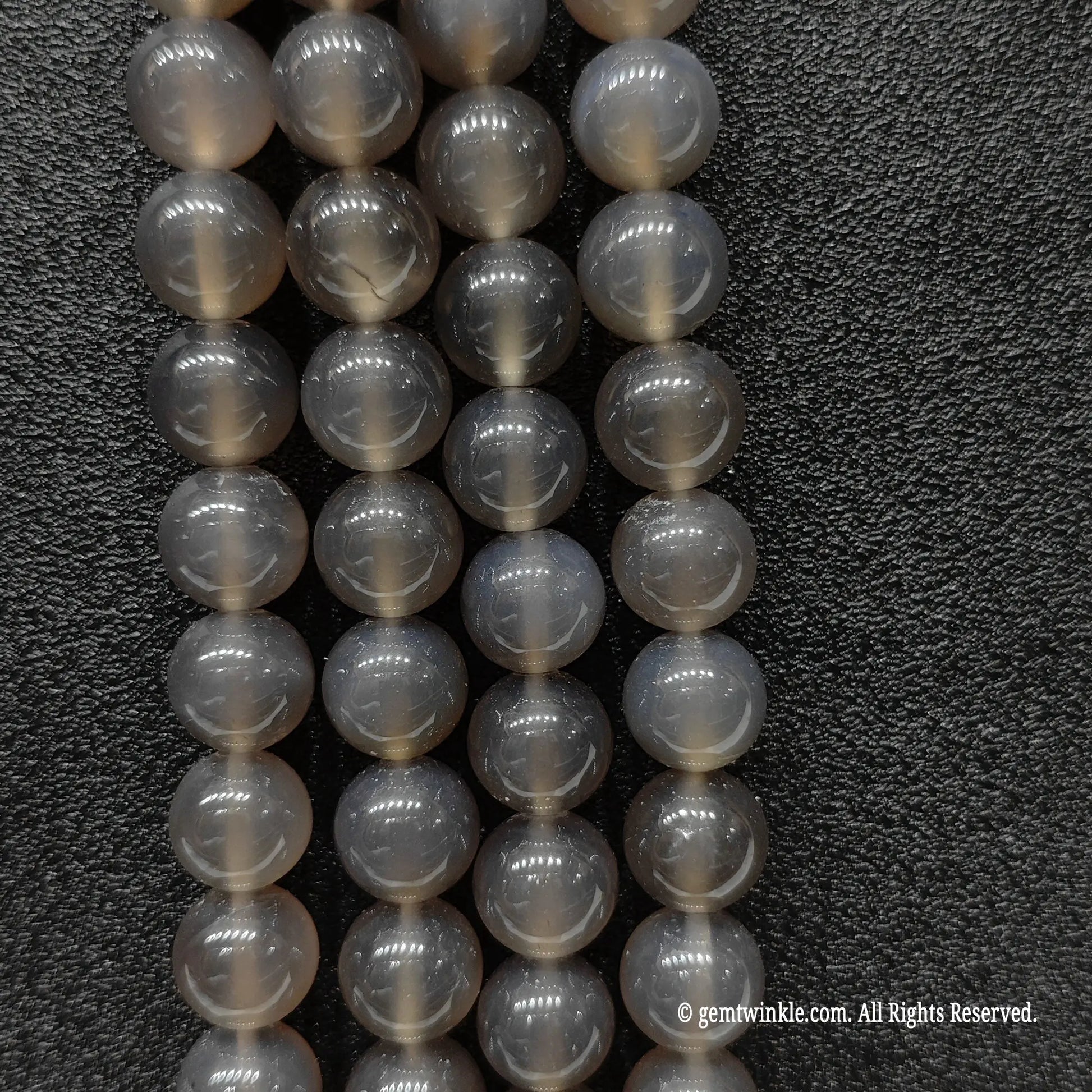 Vertical close up of sleek minimalist grey agate round beads highlighting uniform round cut and glossy surface reflection