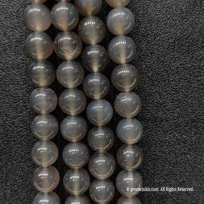 Vertical close up of sleek minimalist grey agate round beads highlighting uniform round cut and glossy surface reflection