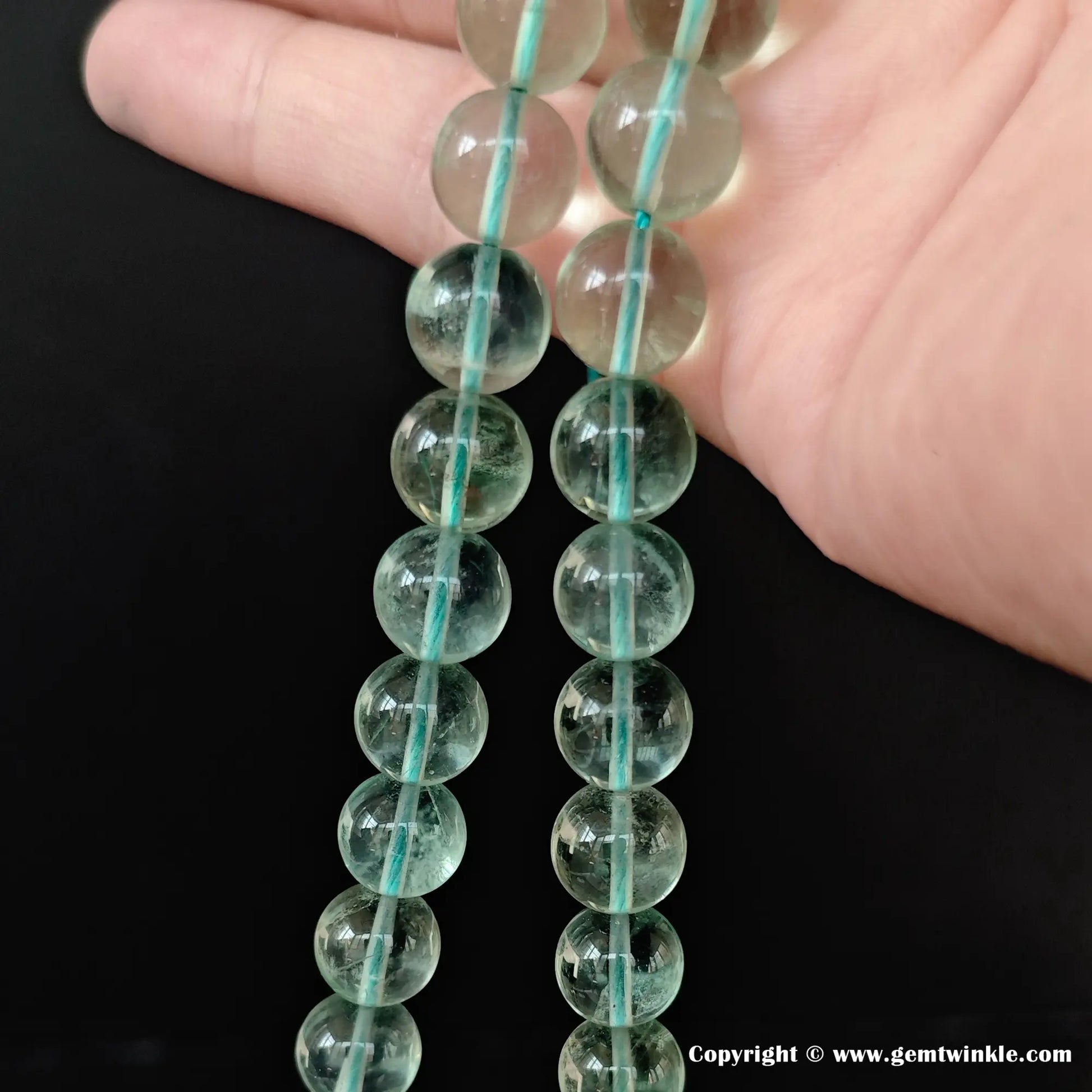 Translucent mint green fluorite crystal bead strands under natural light revealing faint natural inclusions