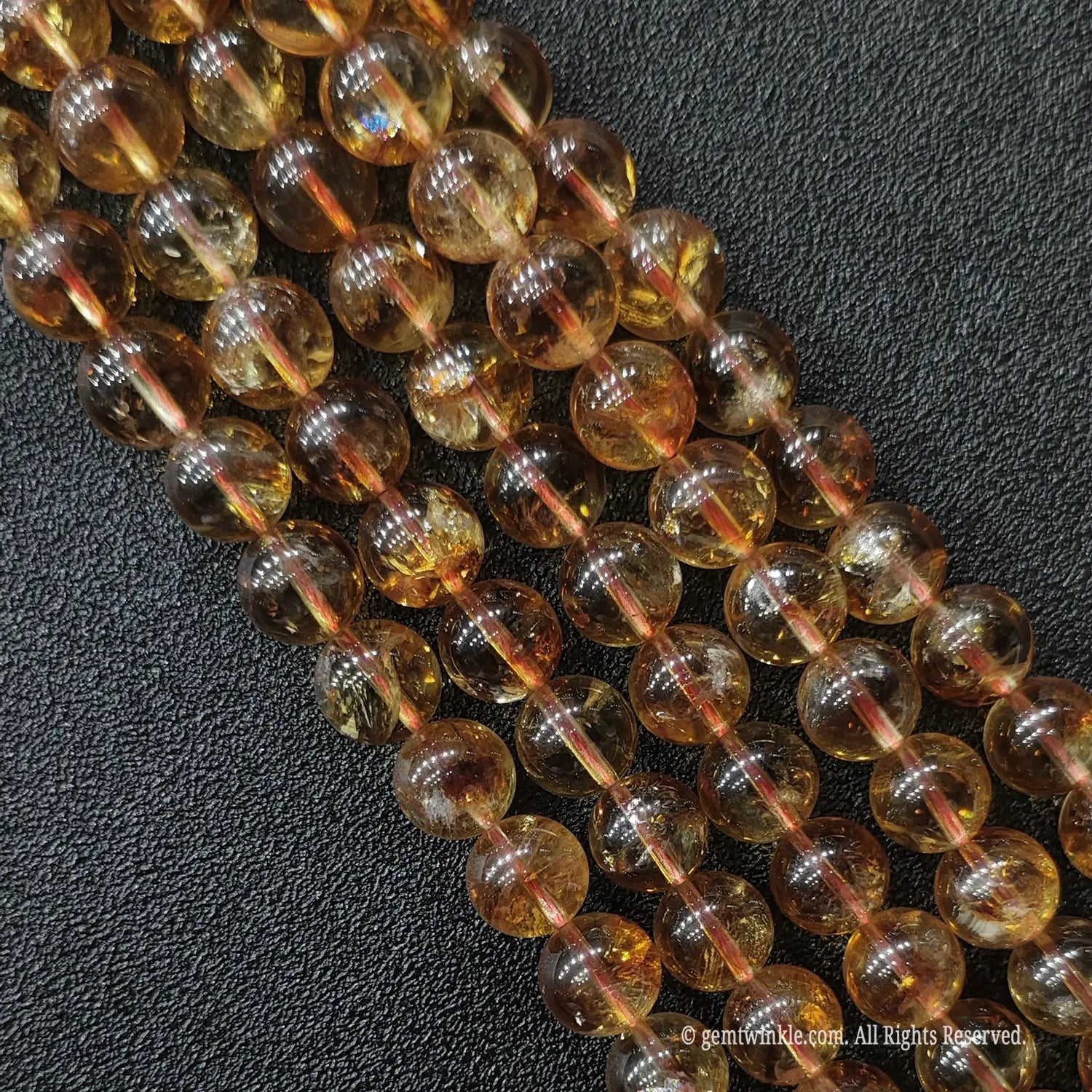 Diagonal neat layout of grade a misty golden tower phantom quartz gemstone strands showing fine character under studio light