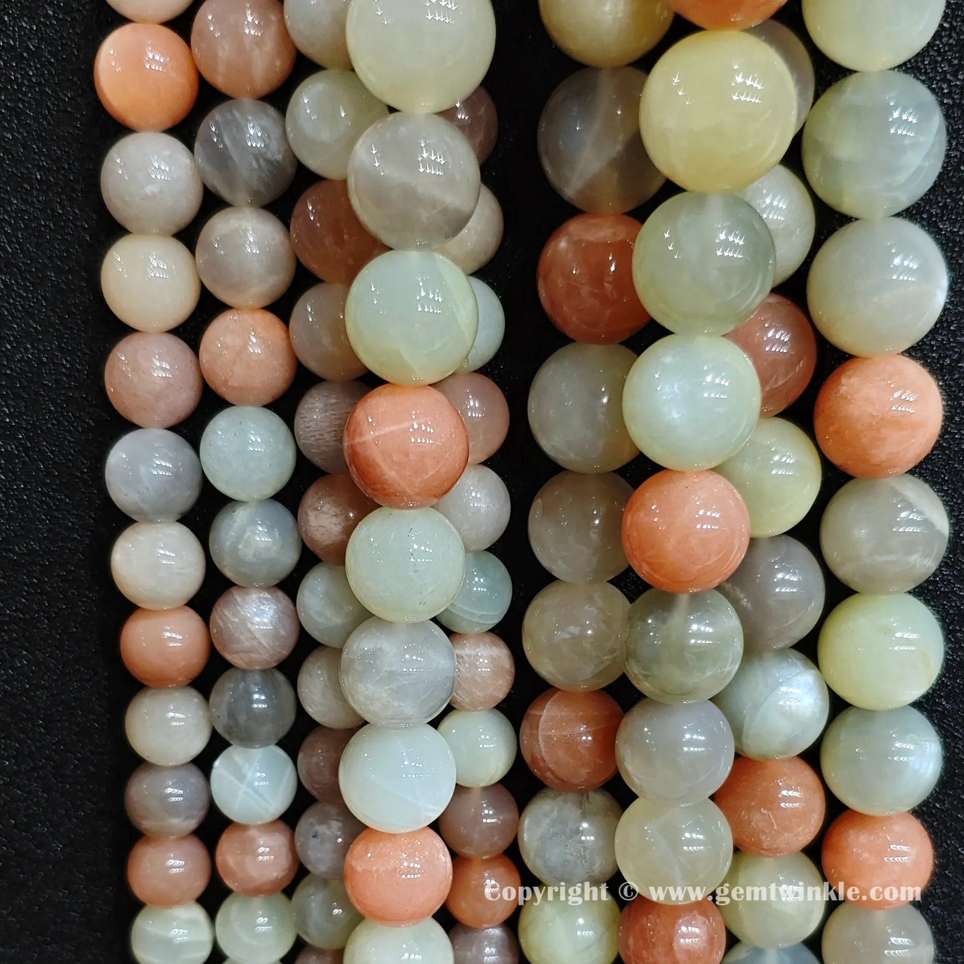 Close up view of natural moonstone sunstone blend round beads inspected on fingers for quality preview