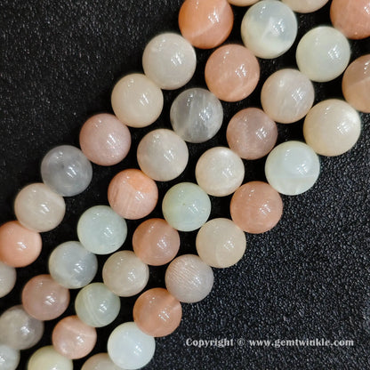 Angled view of natural peach feldspar moonstone sunstone strands arranged parallel on dark background