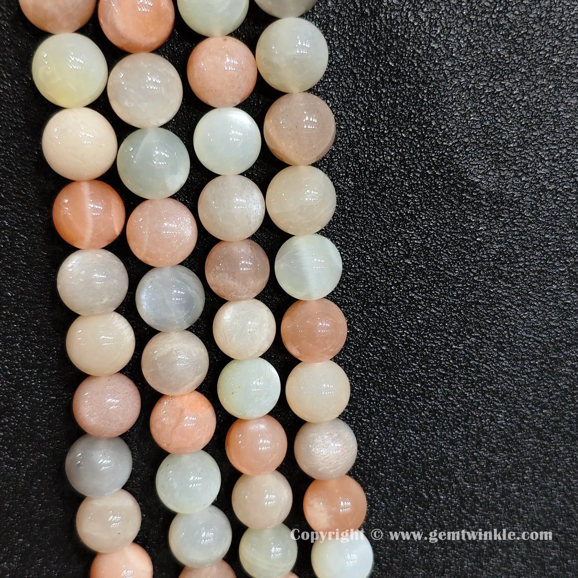 Perspective view of moonstone sunstone blend round beads displaying silky polish across multiple sizes