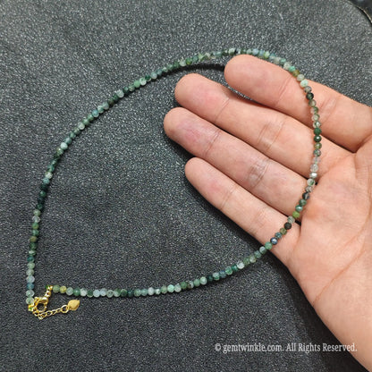 Hand holding 3mm micro faceted moss agate choker showing green botanical inclusions inside clear chalcedony