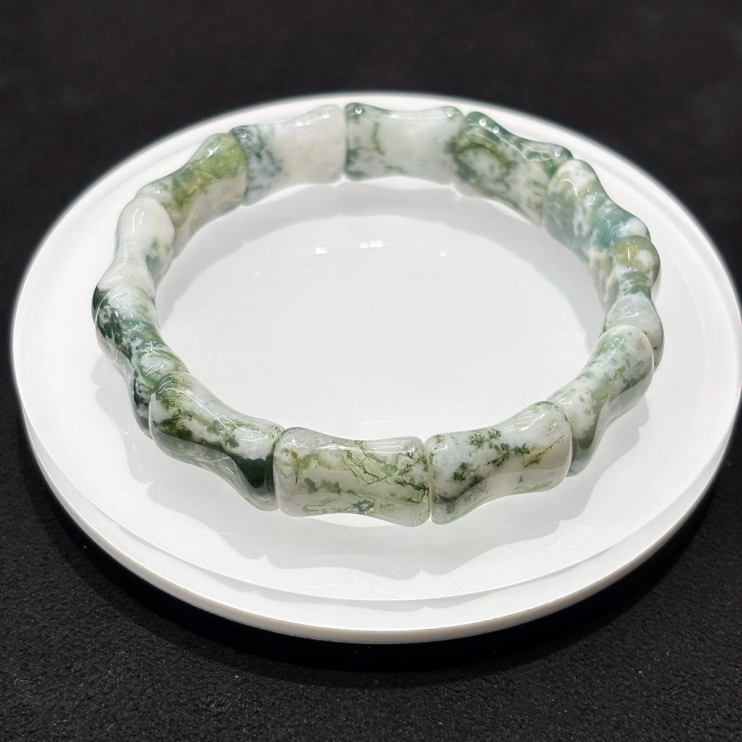 Lifestyle photo of a natural moss agate bamboo bead bracelet, styled with other accessories for a boho-chic look.