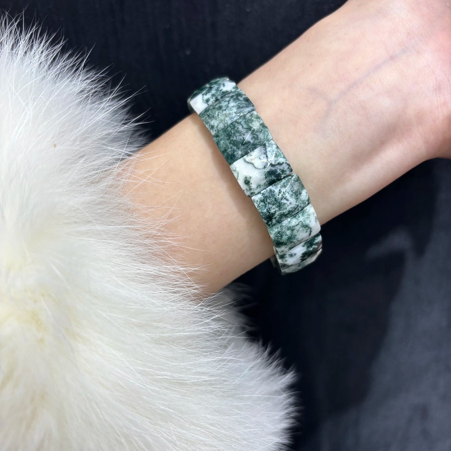 A person wearing a green moss agate bamboo bangle on their wrist, showcasing how the natural stone bracelet fits comfortably for daily wear.