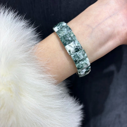 A person wearing a green moss agate bamboo bangle on their wrist, showcasing how the natural stone bracelet fits comfortably for daily wear.