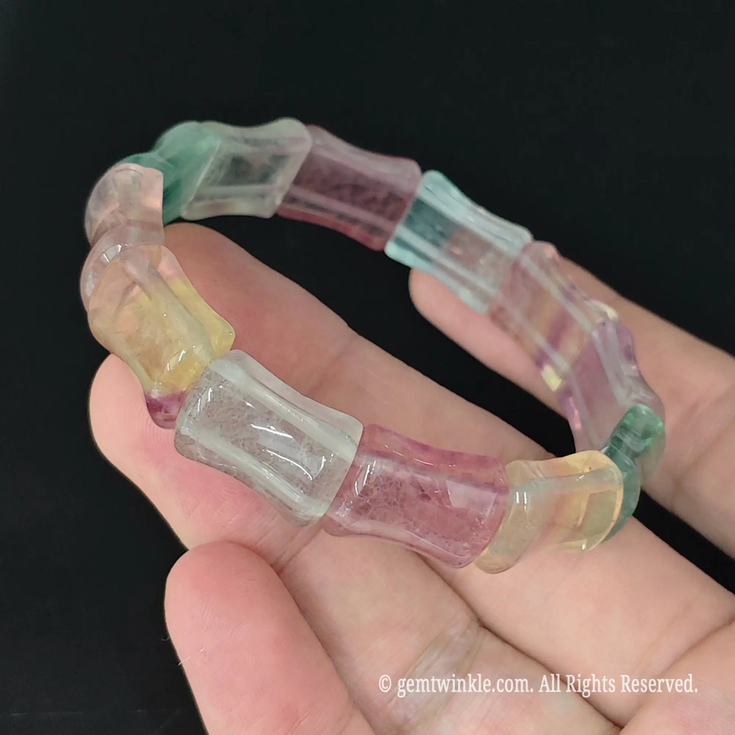 side angle view of 14mm carved rainbow fluorite bamboo segment bracelet on palm