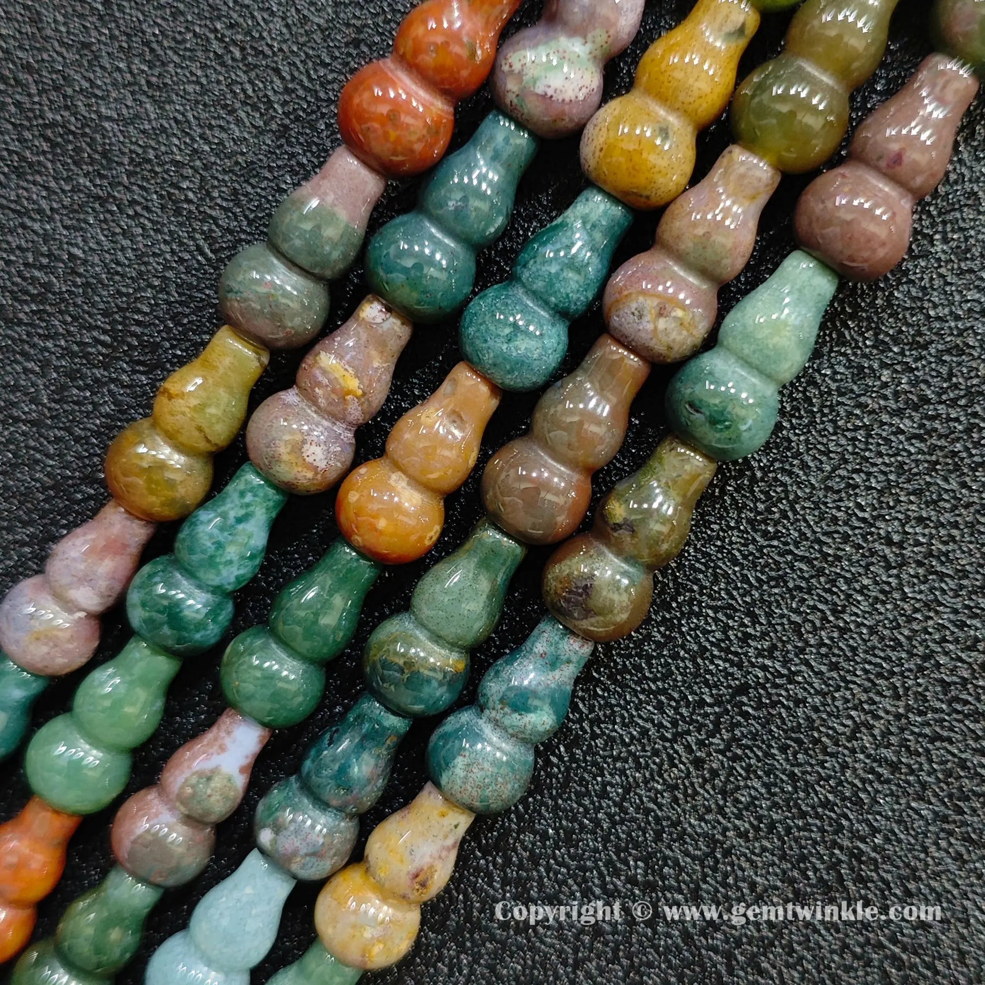 Angled view of multi color natural ocean jasper gourd shaped gemstone strands