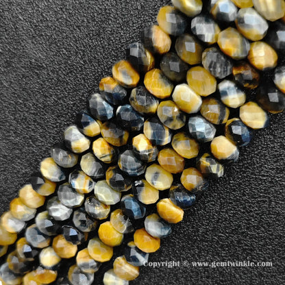 Angled view of multi color tiger eye faceted disc bead strands laid parallel on dark surface
