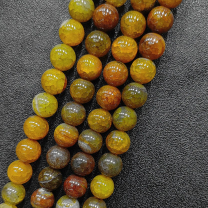 Three wholesale strands of multi tone yellow crackled agate round beads demonstrating consistent cut and gloss