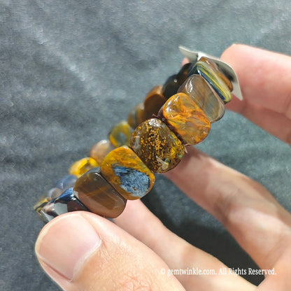 Close up view of multicolor pietersite plate beads showing smooth polish and chaotic gold and blue fibers[cite: 6]