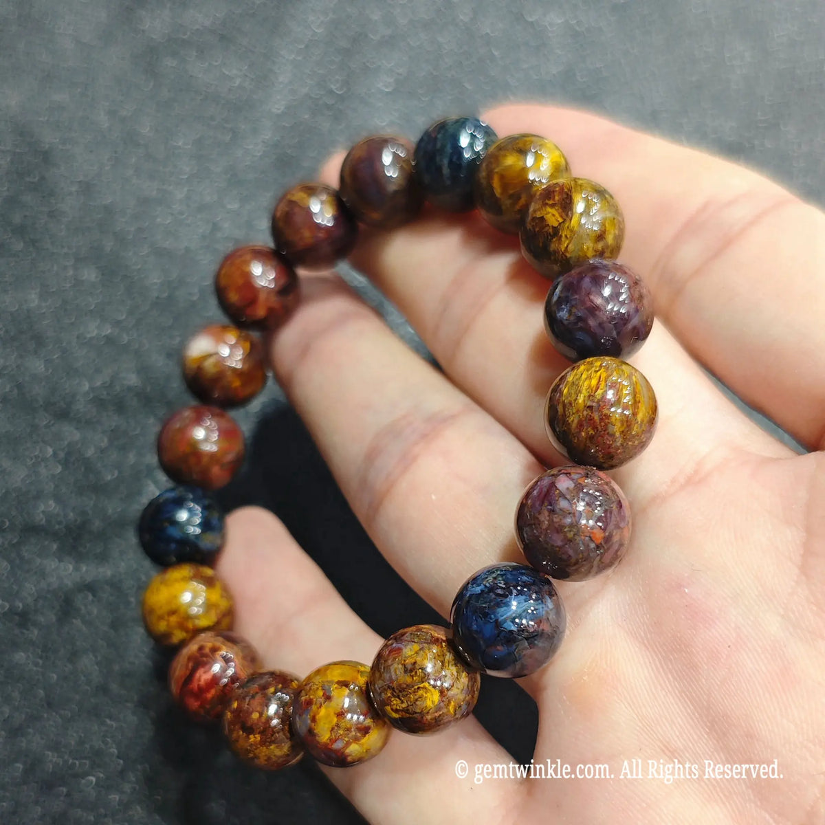Full circle view of a multicolor tempest stone stretch bracelet resting on hand showing natural swirling patterns