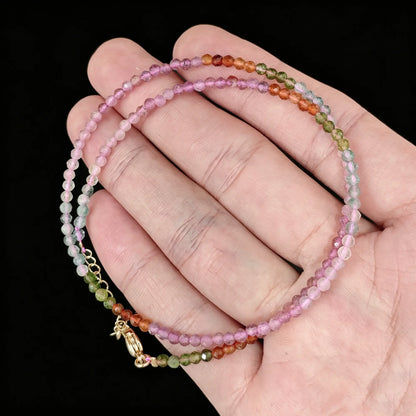 multicolor tourmaline micro faceted bead strand held in hand with gold clasp