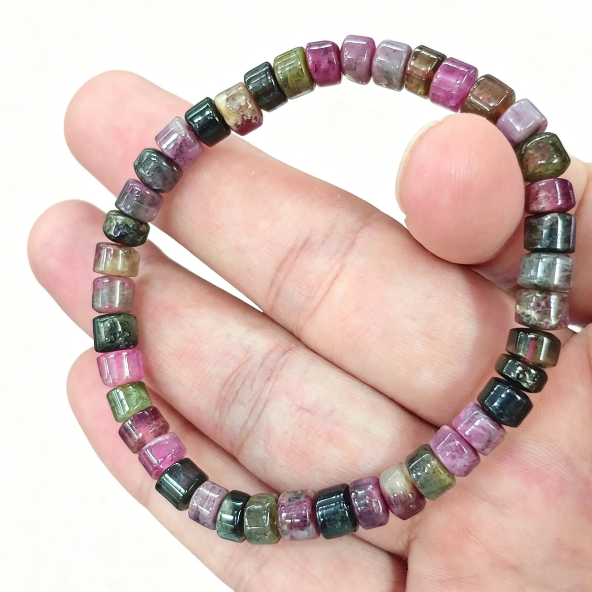 Multicolor tourmaline bracelet held in hand showing 5.5mm cylinder rondelle beads in pink and green hues