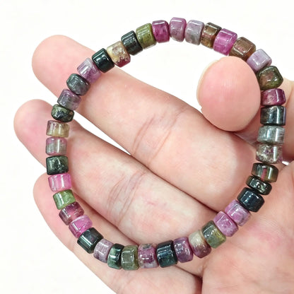 Multicolor tourmaline bracelet held in hand showing 5.5mm cylinder rondelle beads in pink and green hues