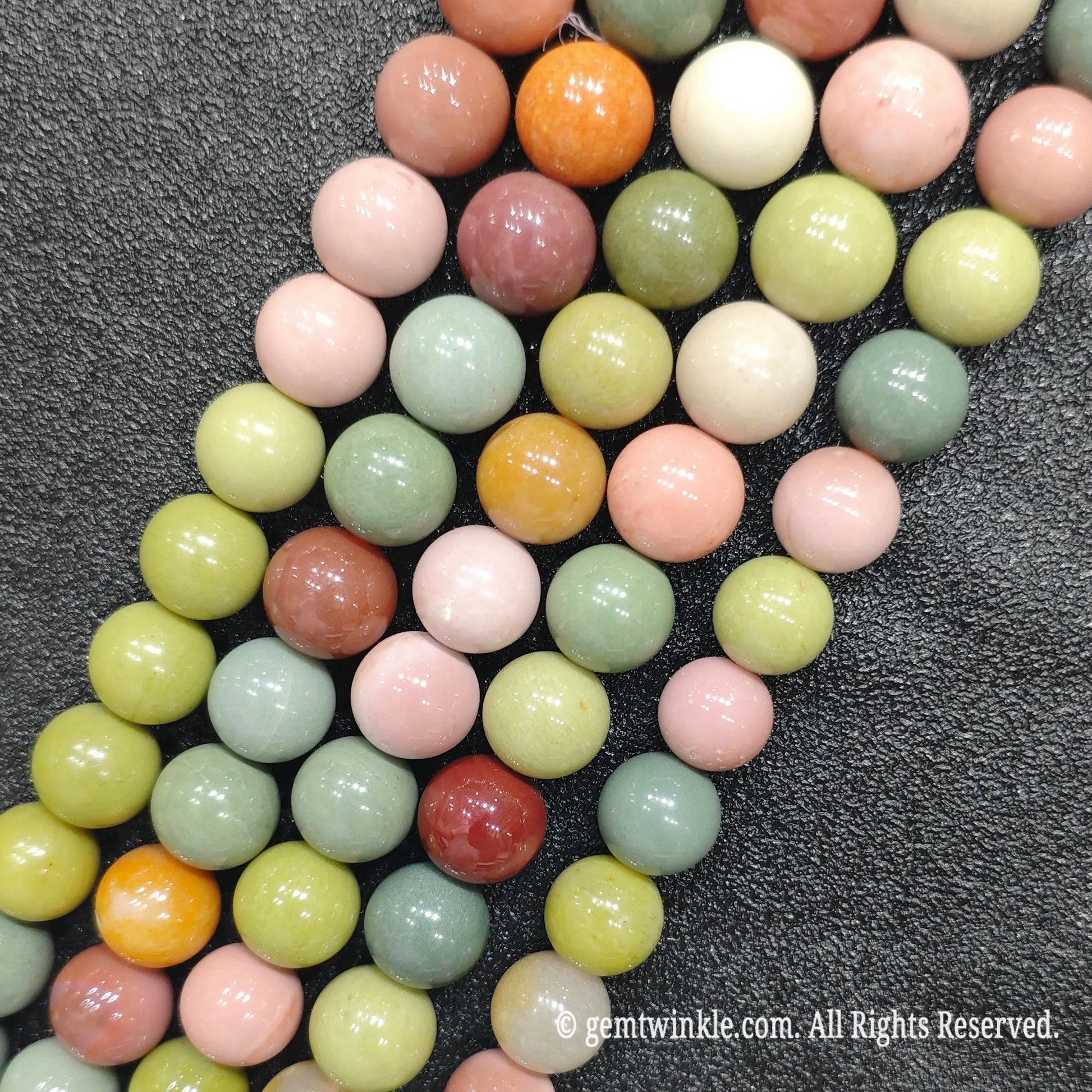 Multiple strands of natural Alashan Gobi agate round loose beads laid together showing colorful mineral assortment