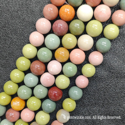 Multiple strands of natural Alashan Gobi agate round loose beads laid together showing colorful mineral assortment