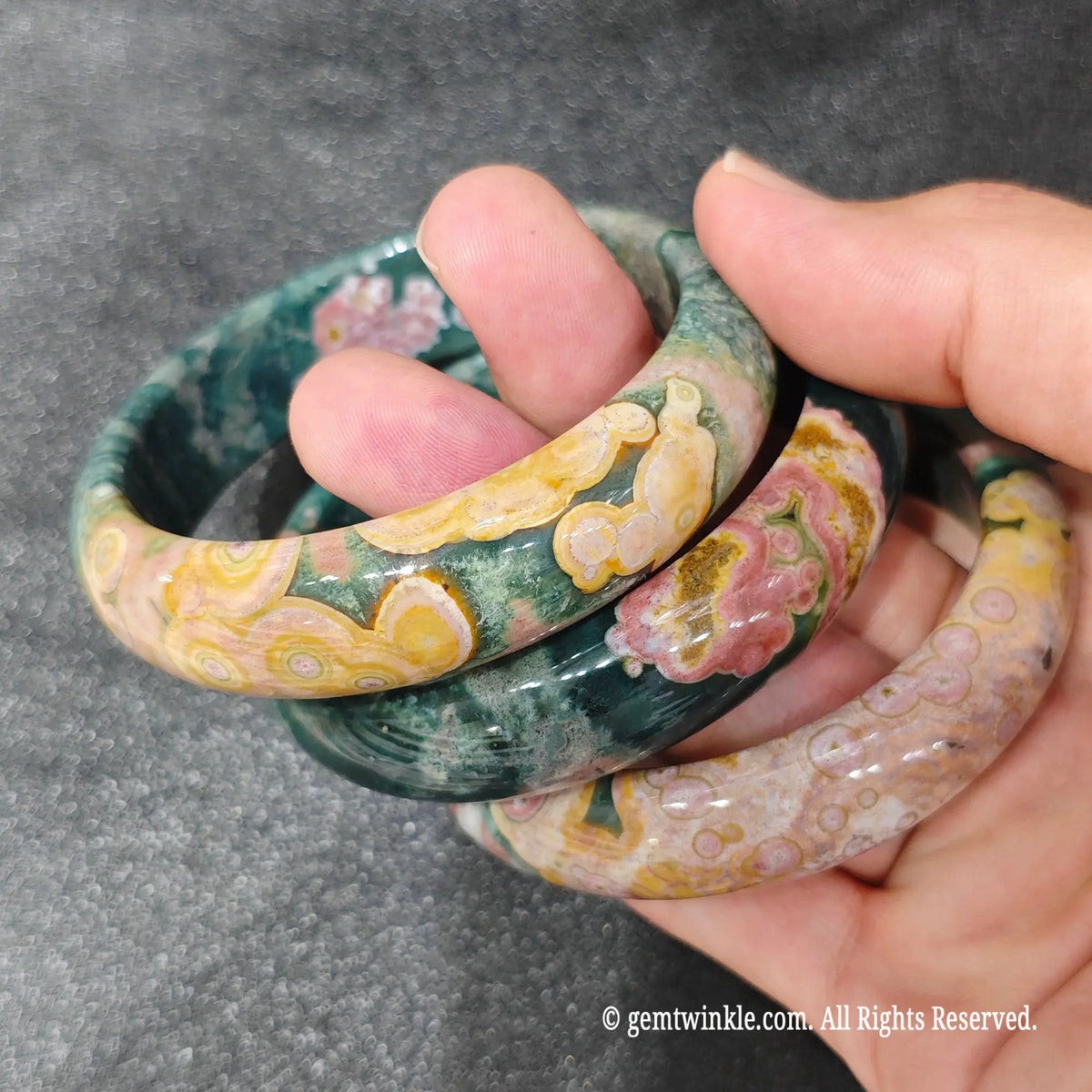 Close up perspective of a multicolored Madagascar ocean jasper bangle featuring forest green and yellow chalcedony banding
