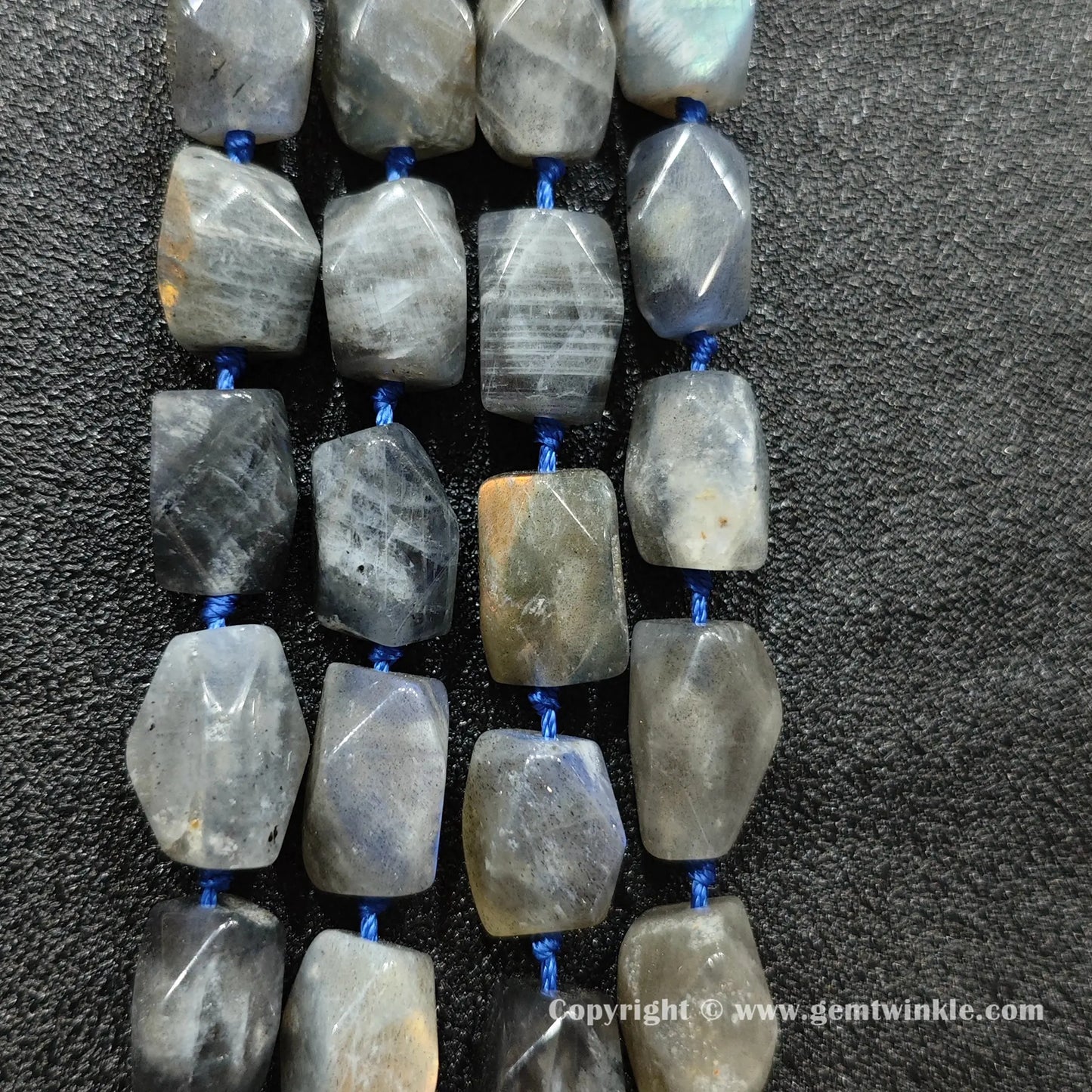 multiple chunky strands of grey moonstone faceted barrel beads on dark texture