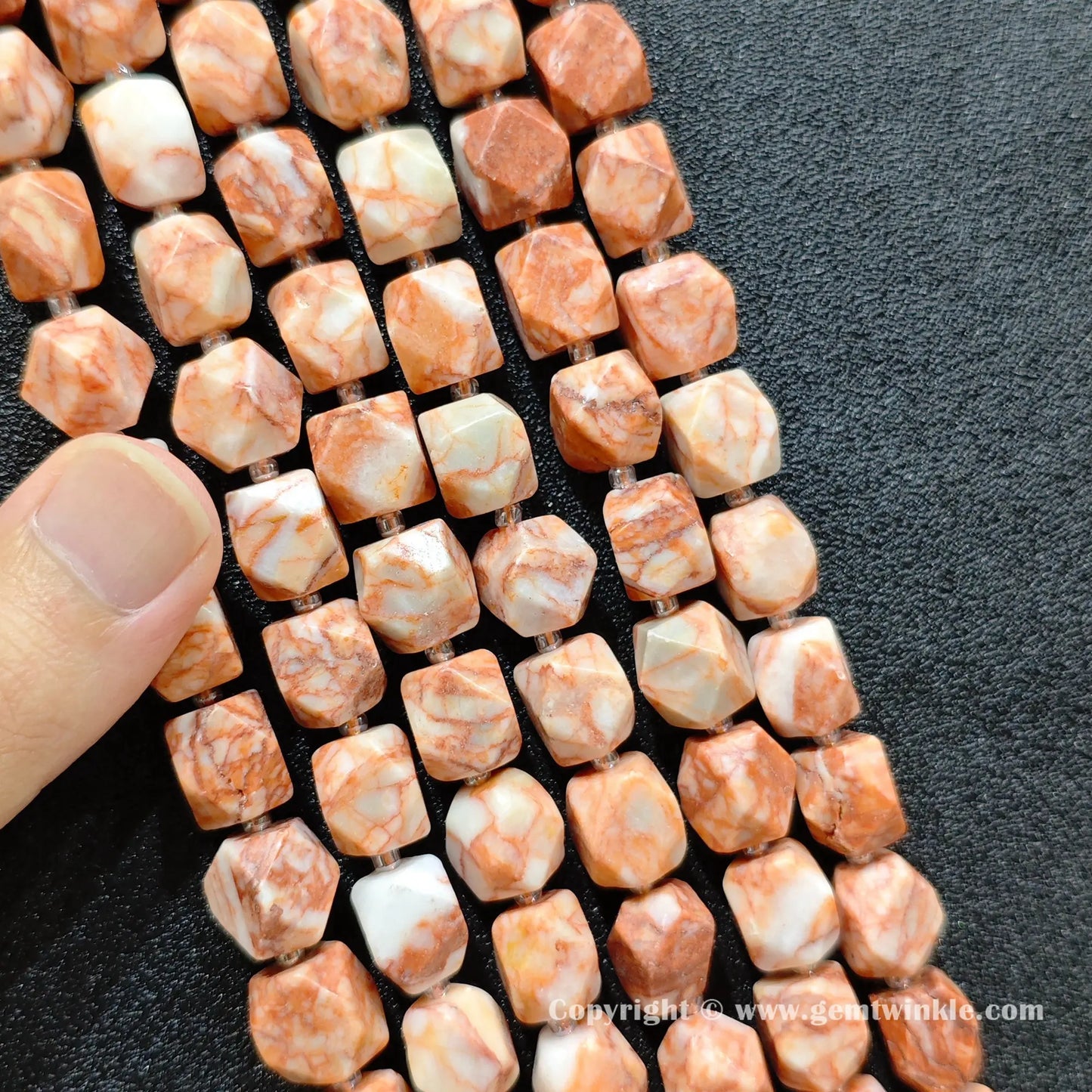 multiple strands of Southwestern red vein stone faceted barrel beads held in hand