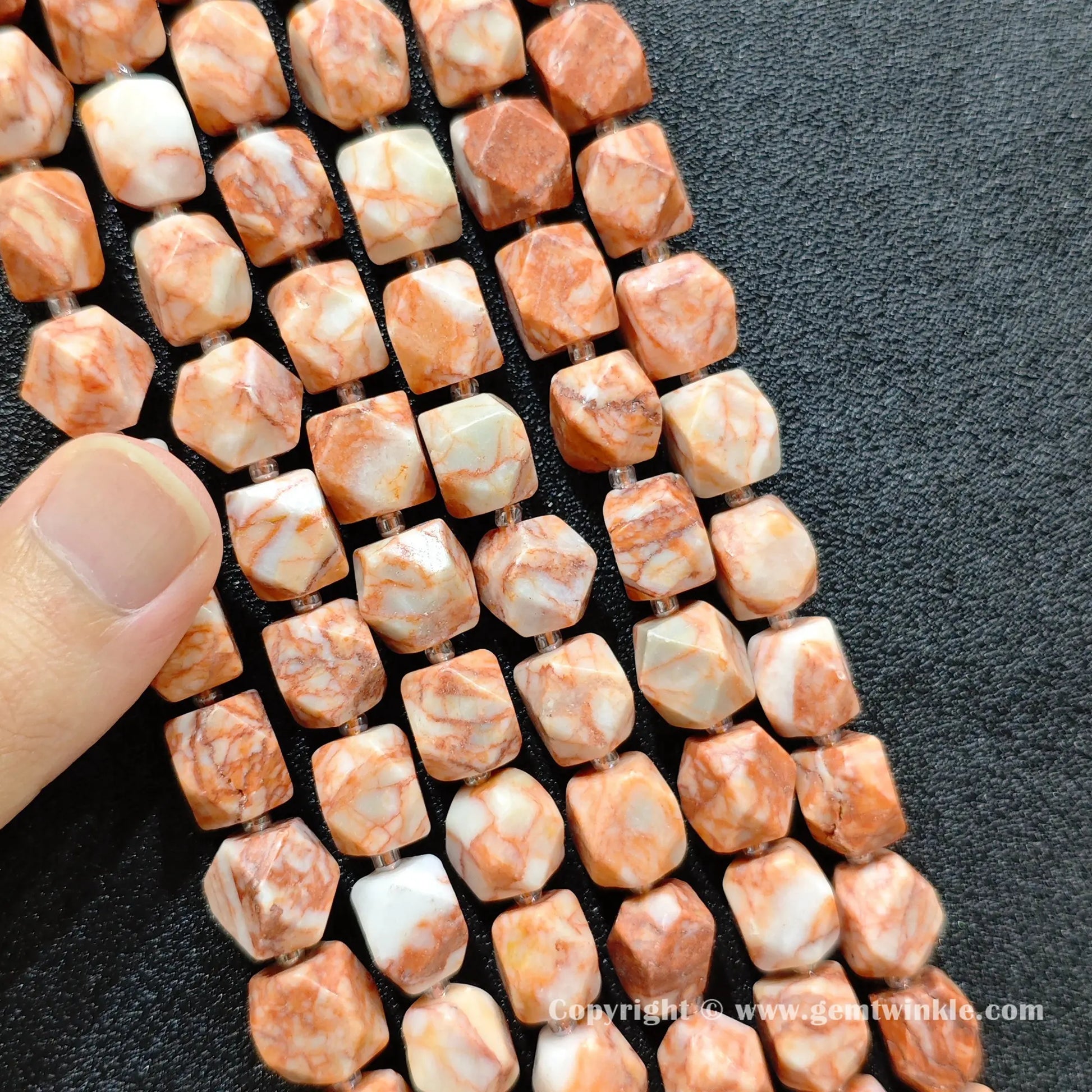 multiple strands of Southwestern red vein stone faceted barrel beads held in hand