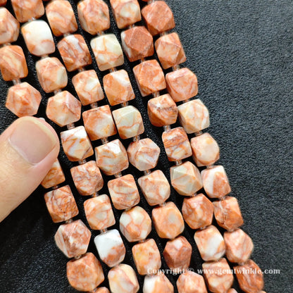 multiple strands of Southwestern red vein stone faceted barrel beads held in hand