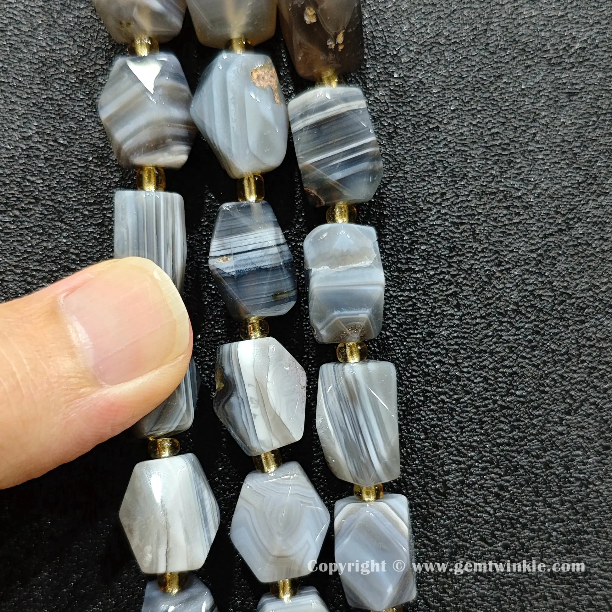 multiple strands of banded persian agate faceted barrel beads on dark texture